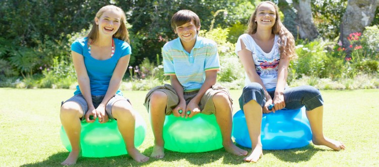 Girls and boy playing on beach balls outdoors